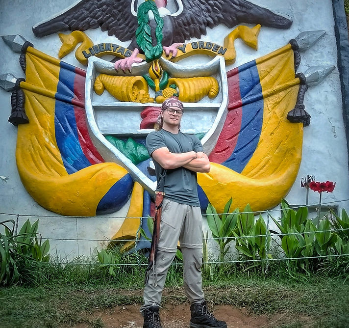 Ernesto Mai standing outdoors in front of a Colombian emblem